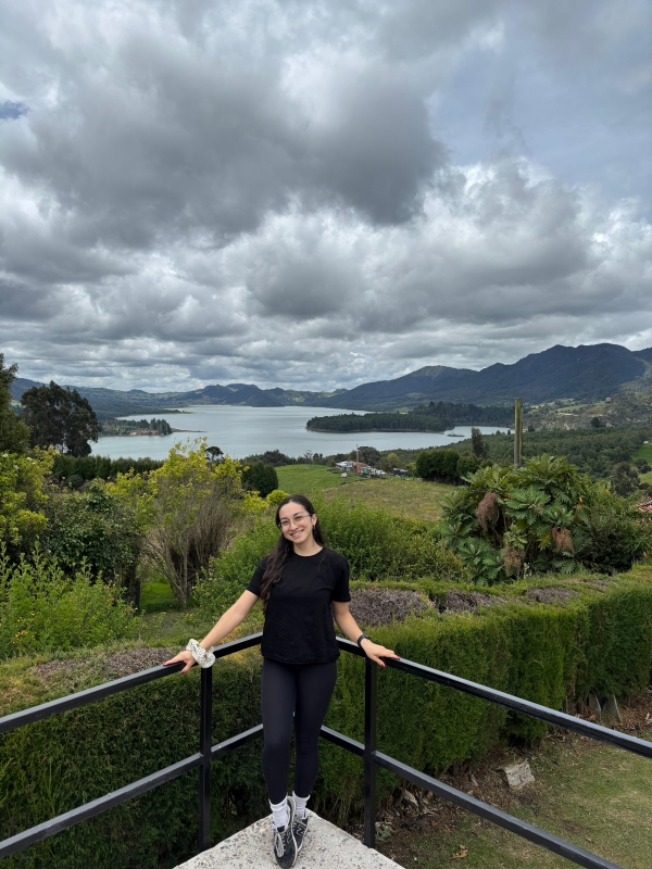 Sofia debout sur un belvédère devant un lac entouré de montagnes